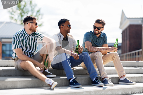 Image of happy male friends drinking beer on street