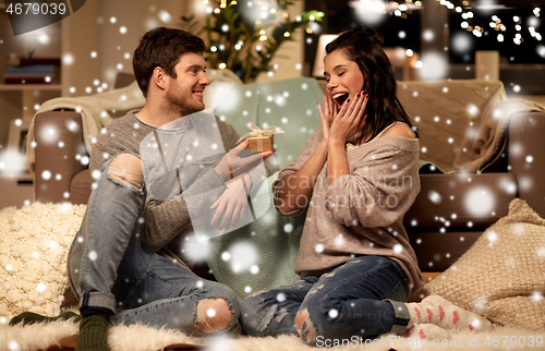 Image of happy couple with gift box at home