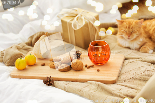 Image of oatmeal cookies, christmas gift and candle in bed