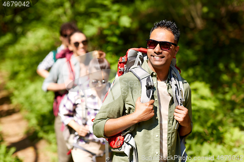 Image of group of friends with backpacks hiking in forest