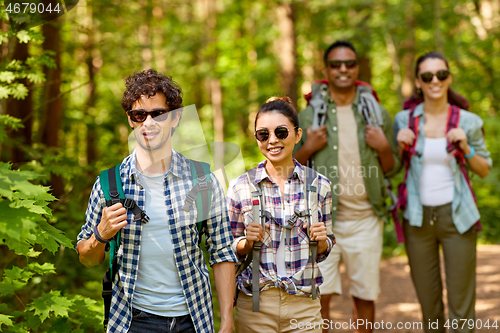 Image of group of friends with backpacks hiking in forest