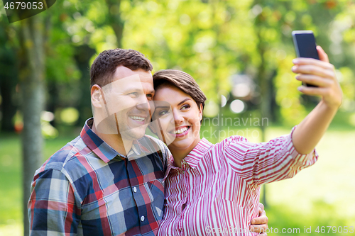 Image of happy couple in park taking selfie by smartphone