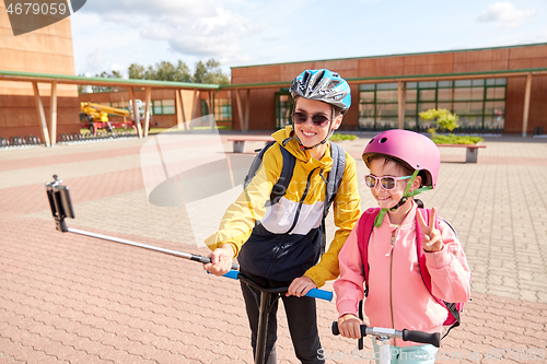 Image of happy school kids with scooters taking selfie