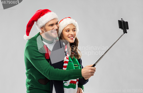 Image of happy couple in christmas sweaters taking selfie