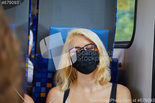 Image of Young woman on a train wearing mask