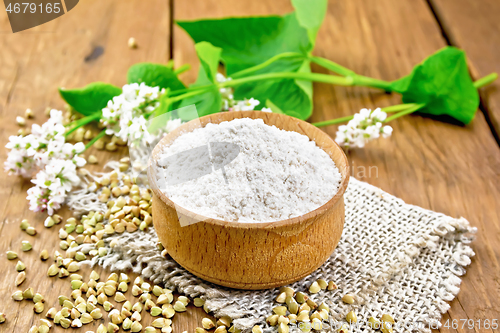 Image of Flour buckwheat green in bowl with flowers on brown board