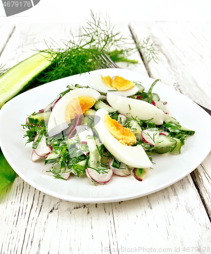 Image of Salad with radish and egg in plate on wooden board