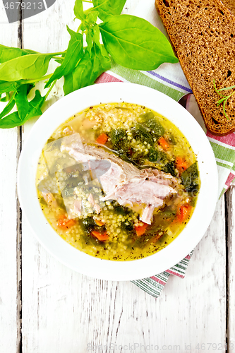 Image of Soup with couscous and spinach in plate on board top