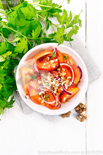 Image of Salad with tomato and walnut in plate on light board top