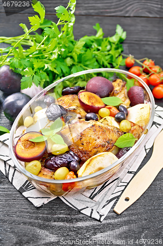 Image of Chicken with fruits and tomatoes in glass pan on dark board