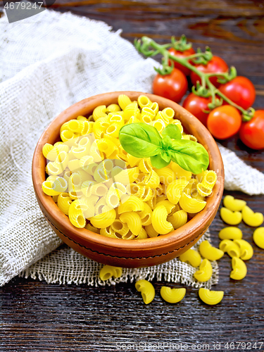 Image of Elbow macaroni in bowl with tomatoes on board