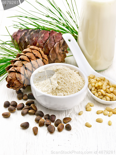 Image of Flour cedar in bowl and nuts in spoon on white board