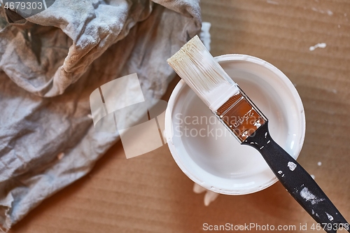 Image of Paint brush on a can of white wall paint