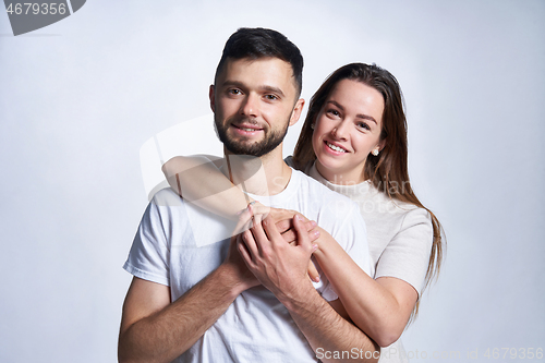 Image of Smiling young couple hugging, studio portrait over light background