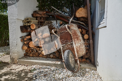 Image of Wheel barrow in the garden by the pile of logs