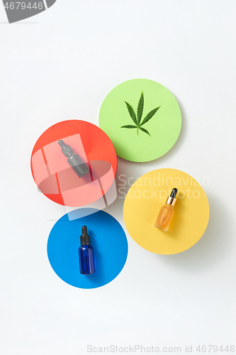 Image of Colorful round cards with bottles of cannabis CBD oil on a light grey background.