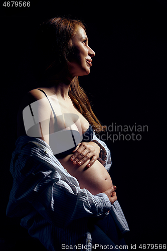 Image of Profile of pregnant woman over black background feeling calmness with closed eyes