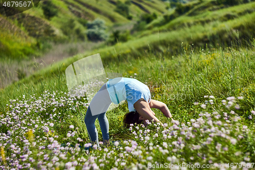 Image of Young woman doing yoga in green summer meadow