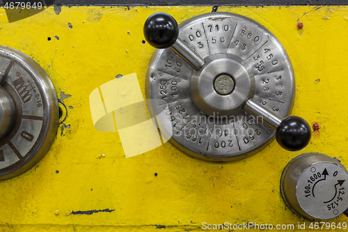 Image of Old yellow lathe machine with a lot of handles.