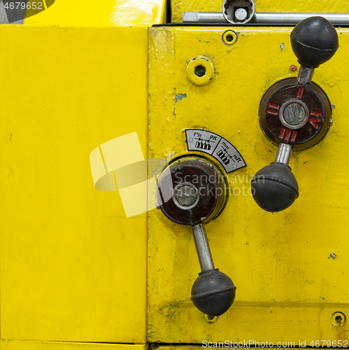 Image of Old yellow lathe machine with a lot of handles.