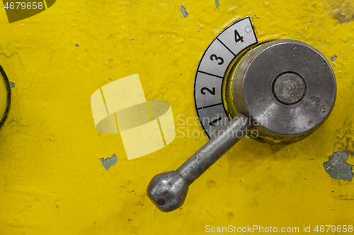 Image of Old yellow lathe machine with a lot of handles.