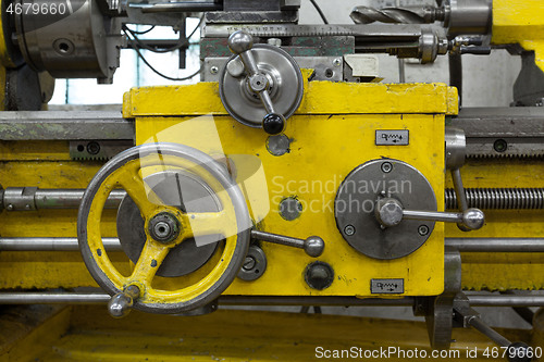 Image of Old yellow lathe machine with a lot of handles.