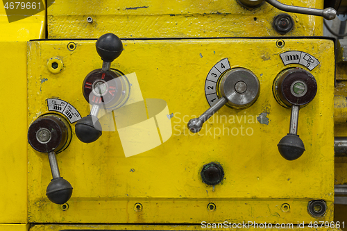 Image of Old yellow lathe machine with a lot of handles.