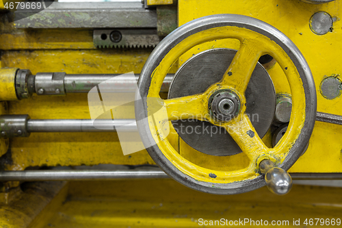 Image of Old yellow lathe machine with a lot of handles.