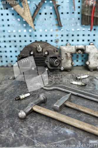 Image of Motorist\'s workplace. Old tools set on metallic table with tools and motorparts