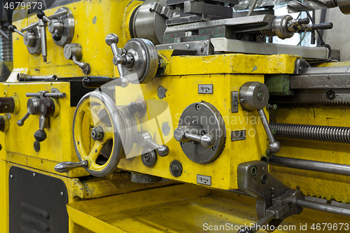 Image of Old yellow lathe machine with a lot of handles.