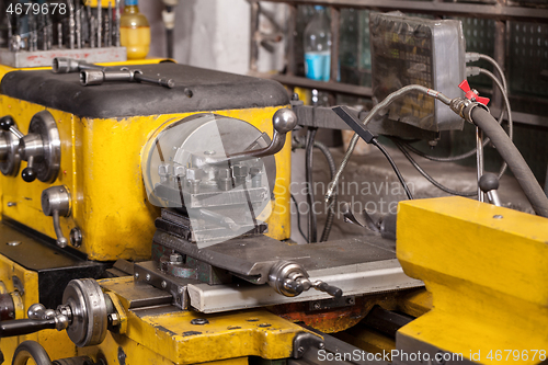 Image of Old yellow lathe machine with a lot of handles.