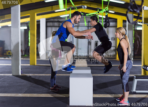 Image of athletes working out  jumping on fit box