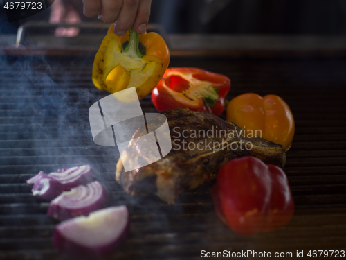 Image of chef cooking steak with vegetables on a barbecue