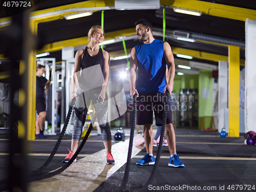 Image of sports couple doing battle ropes crossfitness exercise