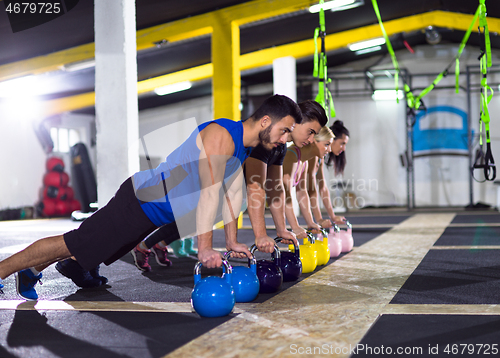 Image of young athletes doing pushups with kettlebells