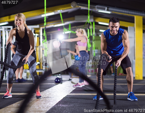 Image of sports couple doing battle ropes crossfitness exercise