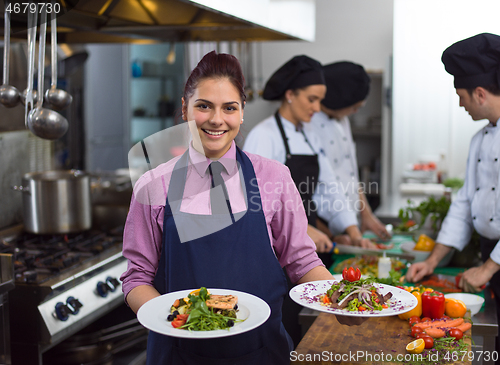 Image of young waitress showing dishes of tasty meals