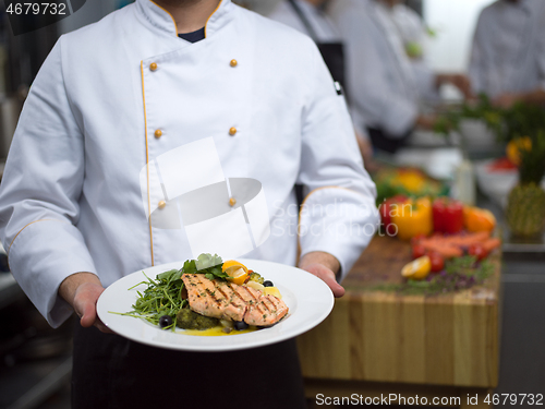 Image of Chef holding dish of fried Salmon fish fillet