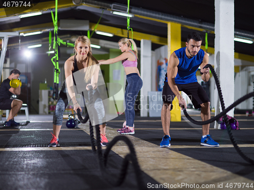 Image of sports couple doing battle ropes crossfitness exercise