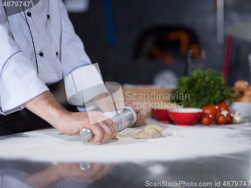 Image of chef preparing dough for pizza with rolling pin