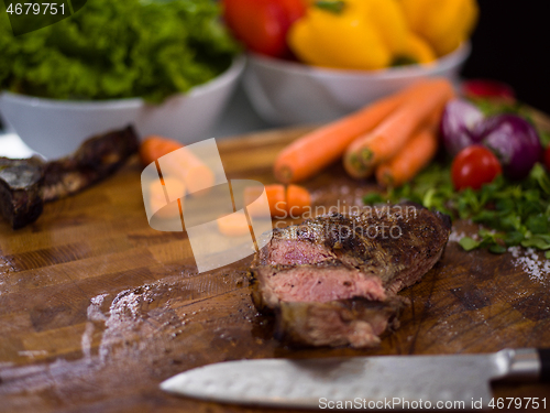 Image of Juicy slices of grilled steak on wooden board