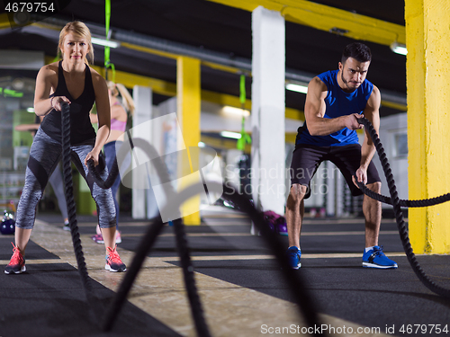 Image of sports couple doing battle ropes crossfitness exercise