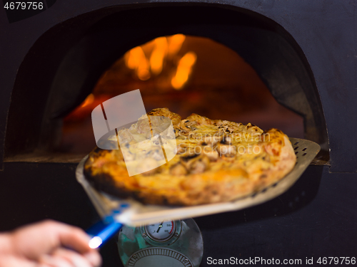 Image of chef removing hot pizza from stove