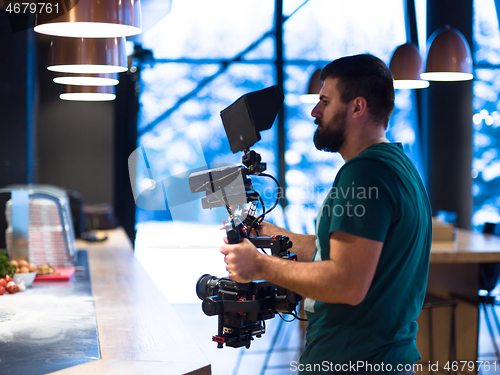 Image of videographer recording while team cooks and chefs preparing meal