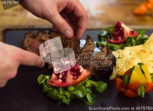 Image of closeup of Chef hands serving beef steak