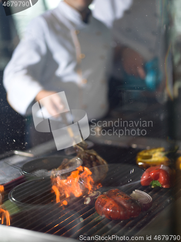 Image of chef cooking steak with vegetables on a barbecue