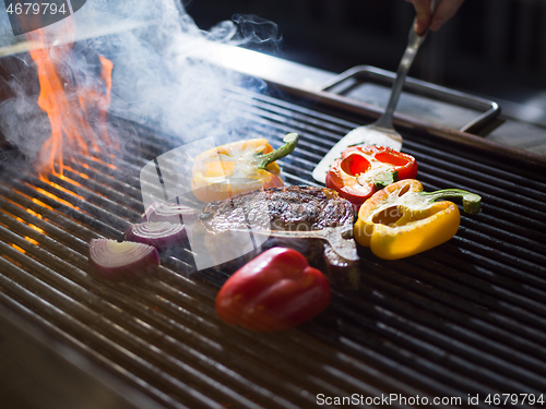 Image of chef cooking steak with vegetables on a barbecue