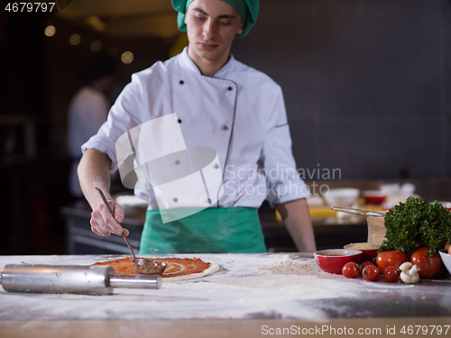 Image of Chef smearing pizza dough with ketchup