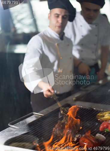 Image of chef cooking steak with vegetables on a barbecue