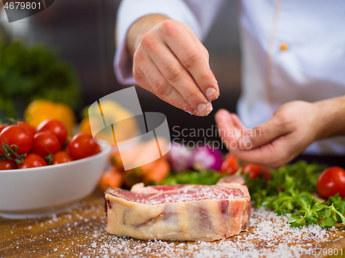 Image of Chef putting salt on juicy slice of raw steak